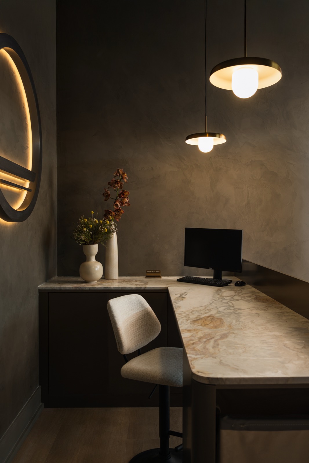 Front desk at Forma with marble counter, pendant lights, and the backlit emblem