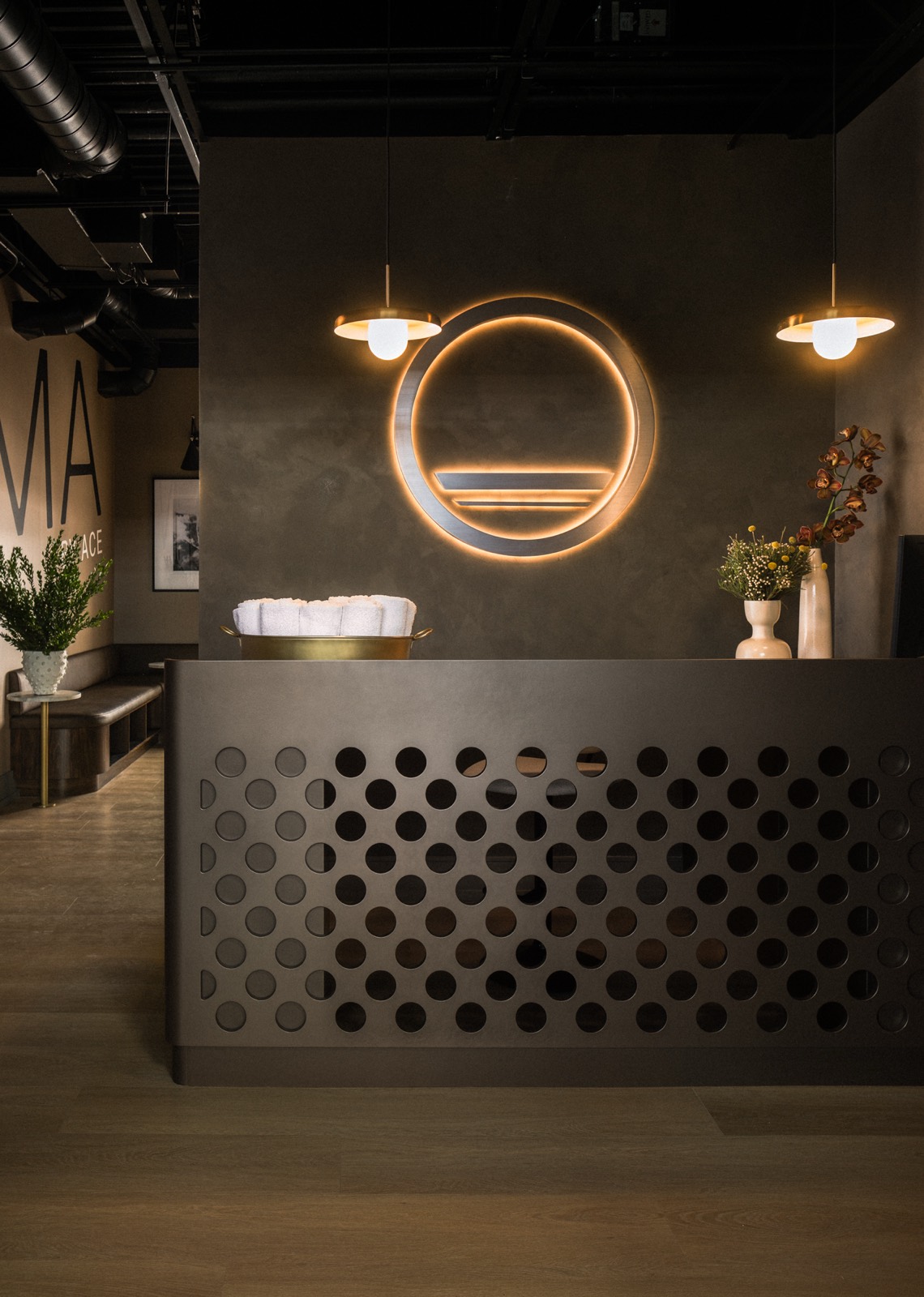 Forma reception desk with perforated metal front beneath the backlit emblem and pendant lights