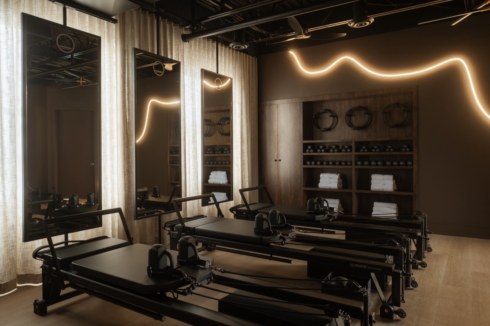Row of reformers in the Forma studio with mirrors and a neon light along the wall
