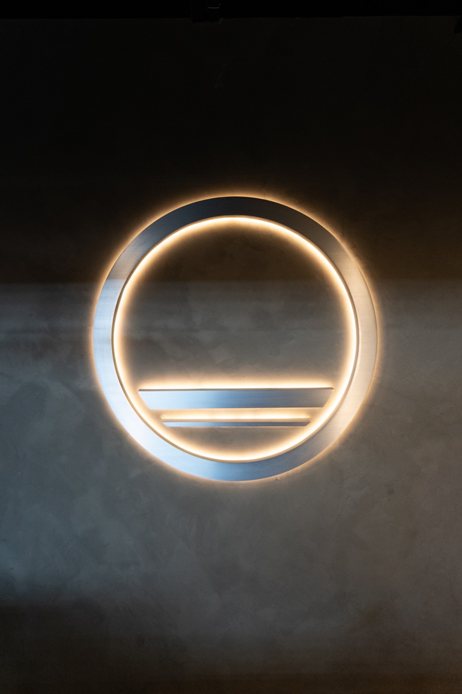 Backlit Forma by ACE emblem on a concrete wall in the studio